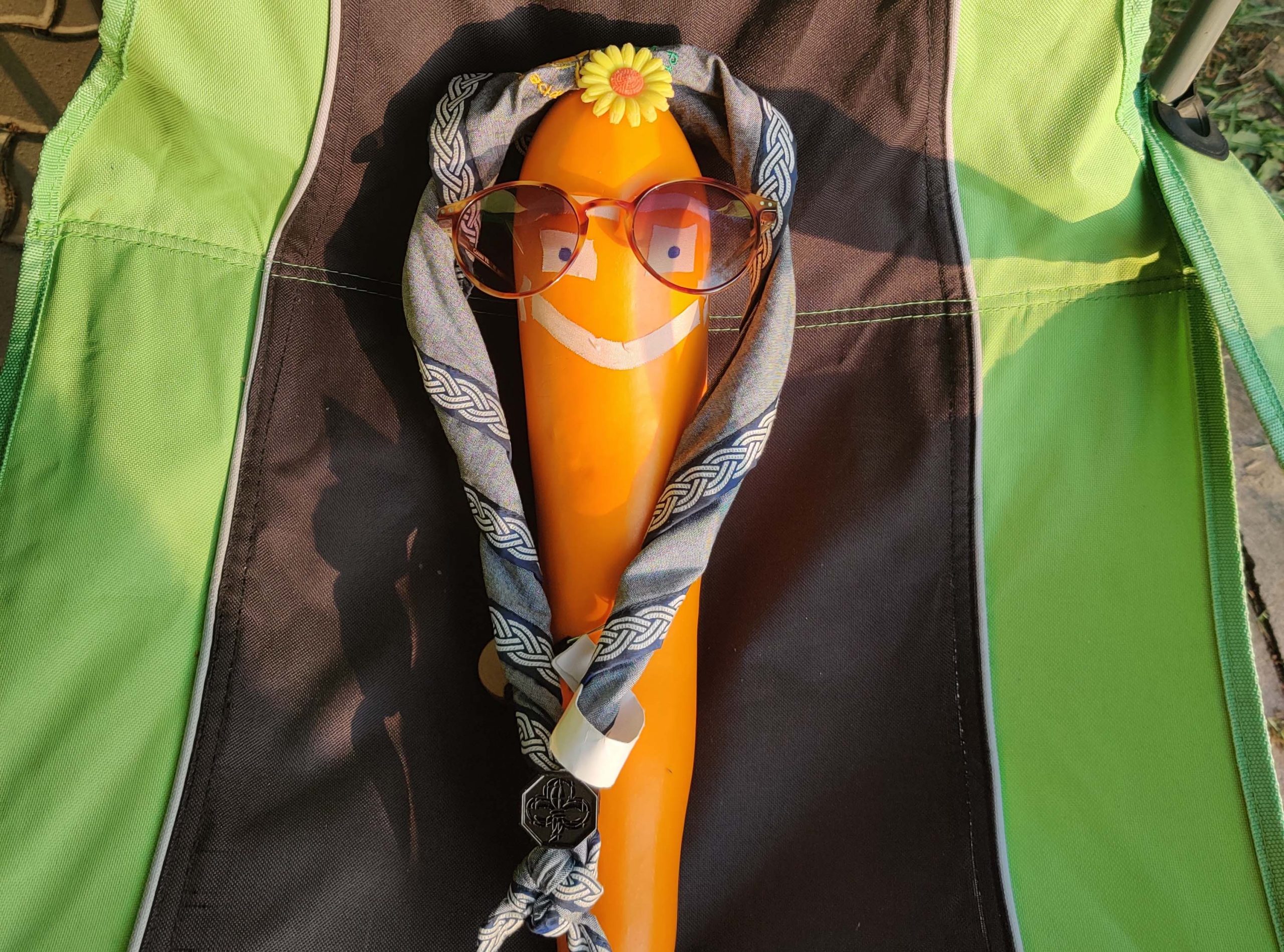 Gelbe Zucchini mit einem Pfadihalstuch, Brille und aufgeklebten Gesicht dekoriert